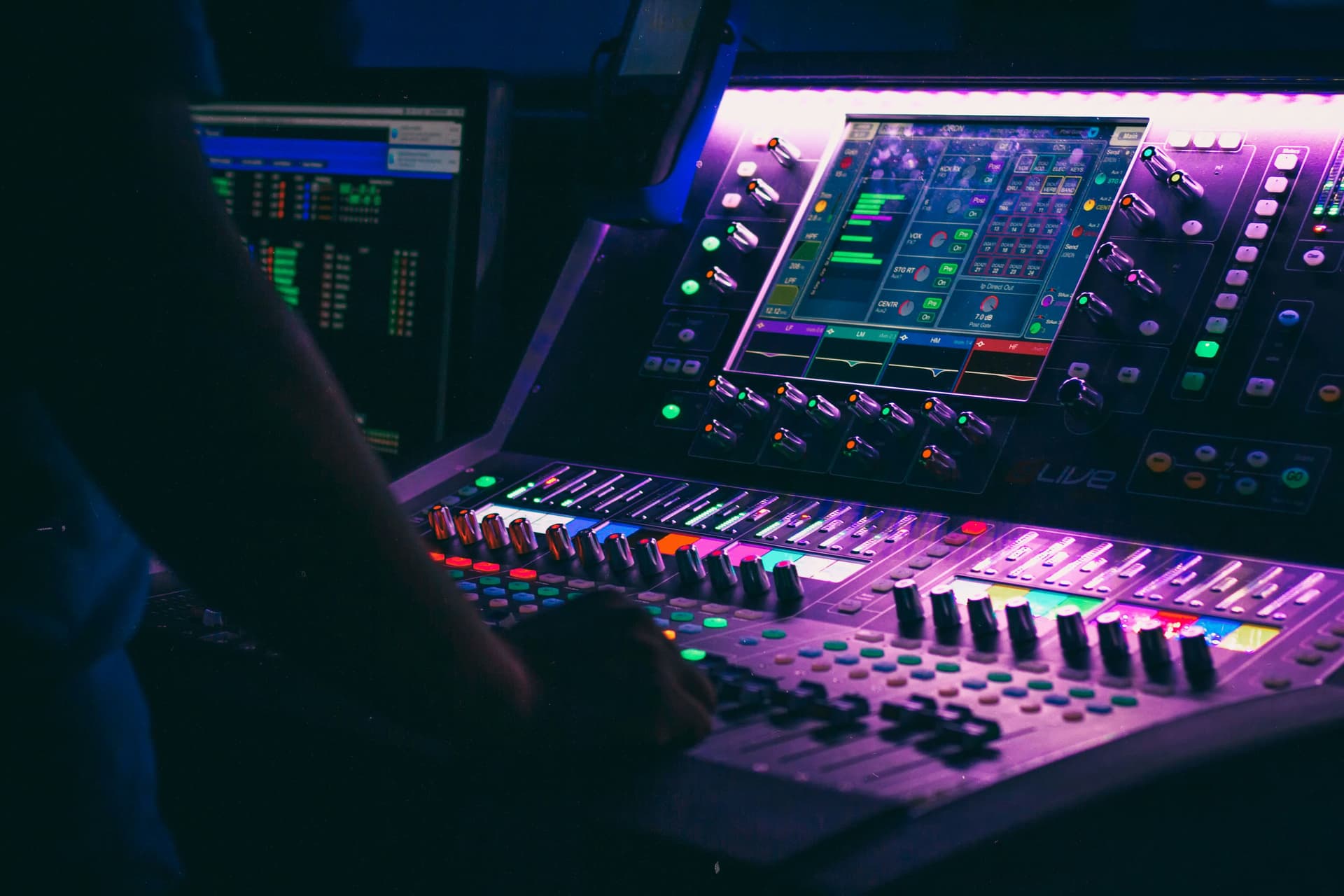 Manos operando una consola de audio en vivo